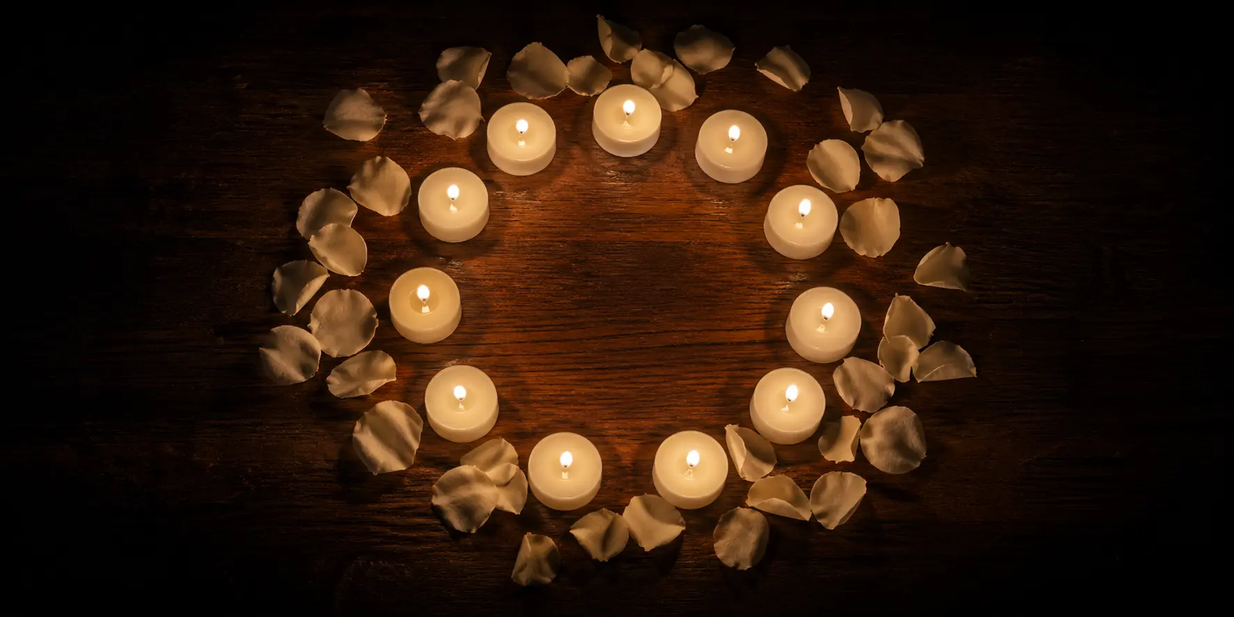 Círculo de velas acesas com pétalas brancas